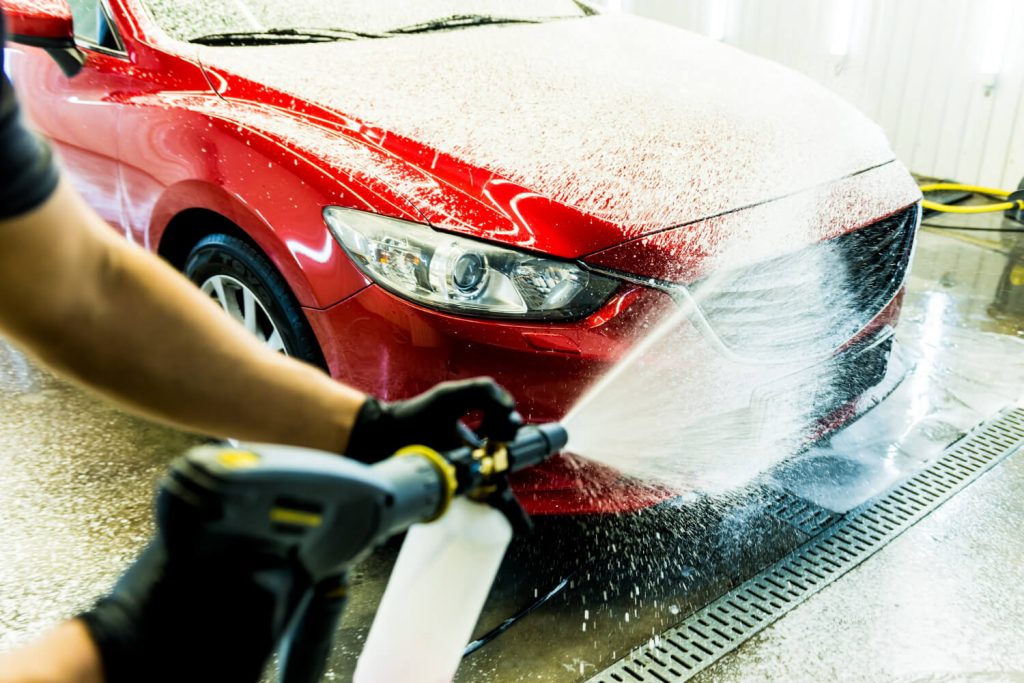 worker washing car with active foam car wash 1